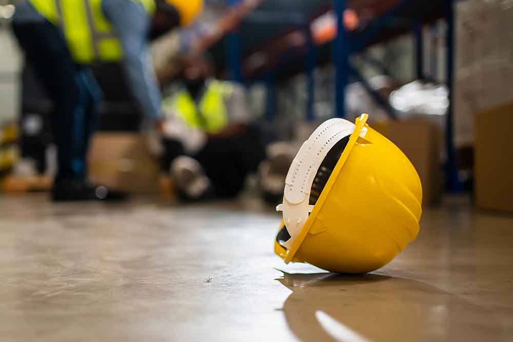 Hard Hat on the ground with an injured employee in the background
