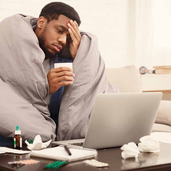 Sick Man Looking at Computer to Make an Appointment Sick Man Looking at Computer to Make an Appointment